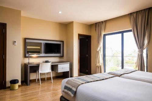马普托WL Hotel Maputo City Center Mozambique Collection的酒店客房配有一张床、一张书桌和一台电视。