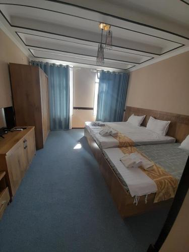 布哈拉Hotel Al Hayit Teracce的酒店客房设有两张床和电视。
