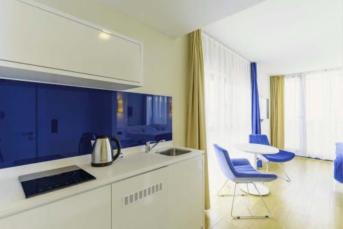 巴统Elegance Sea View Aparthotel In Orbi City Batumi的厨房配有蓝色的椅子、水槽和桌子