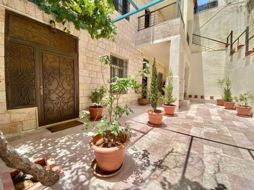 安曼Villa Mira Guesthouse - Downtown Central Amman - AL DIYRIH的门前种有盆栽植物的庭院