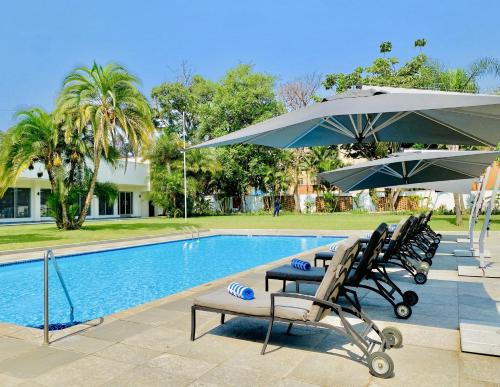 卢萨卡Holiday Inn - Lusaka, an IHG Hotel的一个带两把椅子和遮阳伞的游泳池