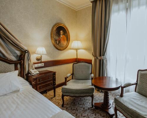 塞哥维亚坎迪多酒店的酒店客房配有一张床、一把椅子和一张书桌