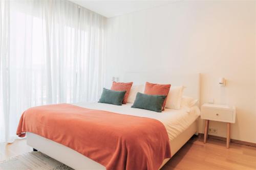 波尔图Oporto Yellow Apartments的一间卧室配有一张带橙色和绿色枕头的大床