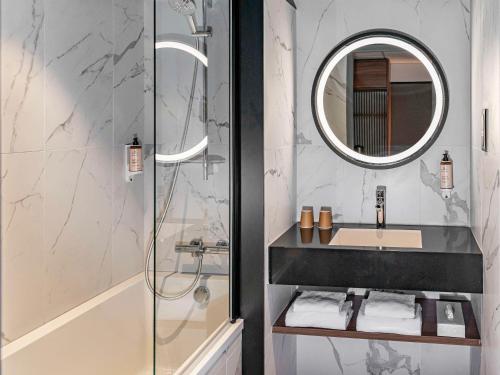 凯恩凯恩中心普莱森斯门美居酒店的浴室配有盥洗盆和带镜子的淋浴