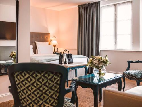 斯特拉斯堡Hotel Cour du Corbeau Strasbourg - MGallery的酒店客房配有床、沙发和桌子。