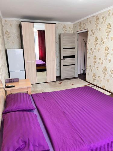 阿特劳Однокомнатная квартира в Жилгородке рядом с ДостарМед的一间卧室,在房间内配有一张大紫色床