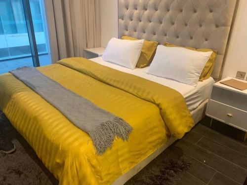 麦纳麦Cloud9 Waterfront Luxury Condo的一张带黄色毯子和枕头的大床