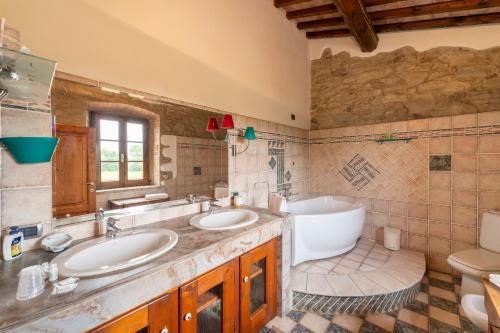基亚恩尼Podere Ostoncino的一间带两个盥洗盆、浴缸和卫生间的浴室