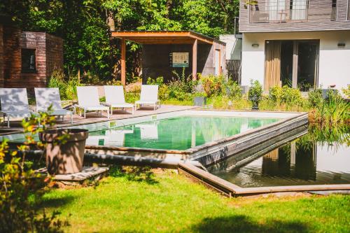 蒙斯Utopia Hotel - Art & Nature Hotel的一个带椅子的庭院和房子的游泳池
