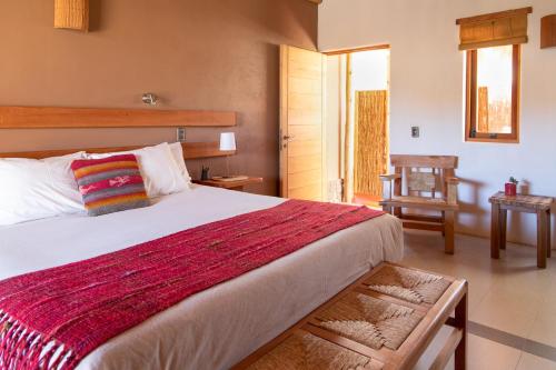 圣佩德罗·德·阿塔卡马Naturalis Hotel的一间卧室配有一张带红色毯子的大床