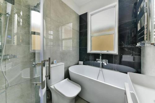 伦敦London 2-Bedrooms Apartment的浴室配有卫生间、浴缸和水槽。