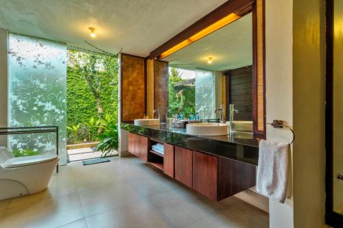 苏卡瓦提Sri Abi Ratu Villas的一间带两个盥洗盆和大镜子的浴室