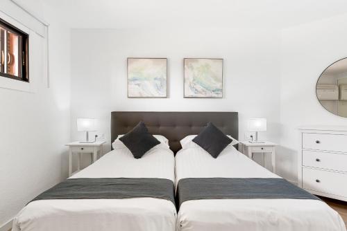 洛斯克里斯蒂亚诺斯鸽子海滩公寓的卧室内的两张床,配有白色的墙壁和镜子
