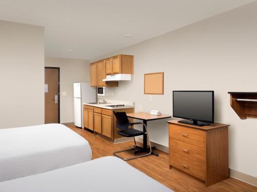 普兰菲尔德Extended Stay America Select Suites - Indianapolis - Plainfield的酒店客房配有一张床和一张书桌及一台电视
