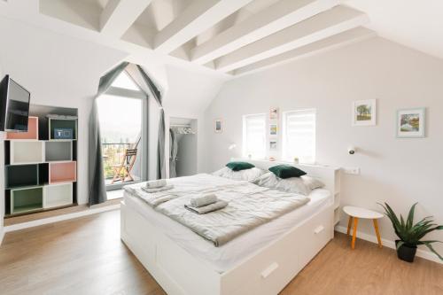 大毛罗什Hársliget Apartman的白色的卧室设有一张白色大床和一个窗户。