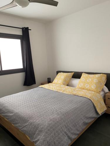 埃唐萨莱莱班海滩Appart Océan的一间卧室配有一张带黄色枕头的床和一扇窗户