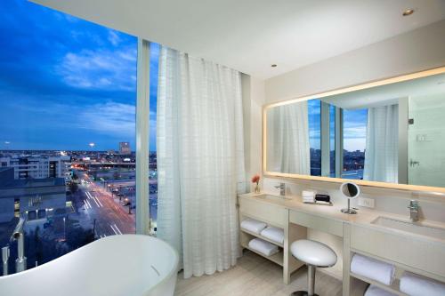 达拉斯HALL Arts Hotel Dallas, Curio Collection by Hilton的带浴缸的浴室和大窗户