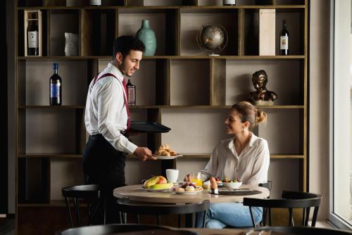 佛罗伦萨iQ Hotel Firenze的餐馆里一个男人和女人准备食物