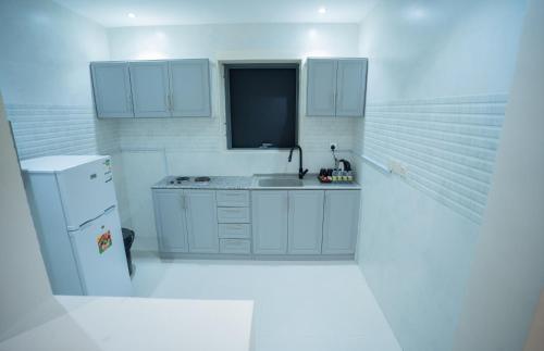 利雅德البرج الازرق شقق فندقية Alburj Alazraq的白色的厨房配有水槽和冰箱