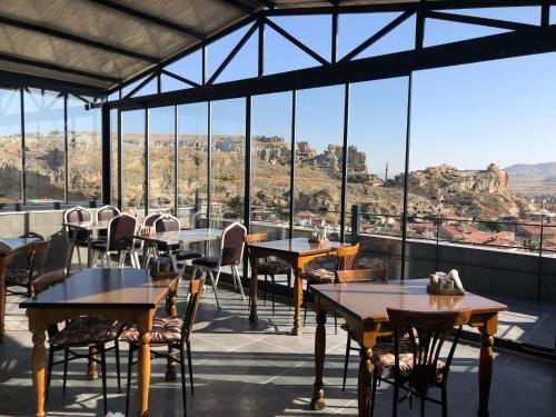 内夫谢希尔Cappadocia Landscape House的餐厅配有桌椅,位于山脉的背景中。