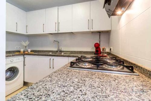 塞维利亚Apartamento 4 en Estadio Sevilla 8 plazas y metro的厨房配有炉灶和洗衣机。