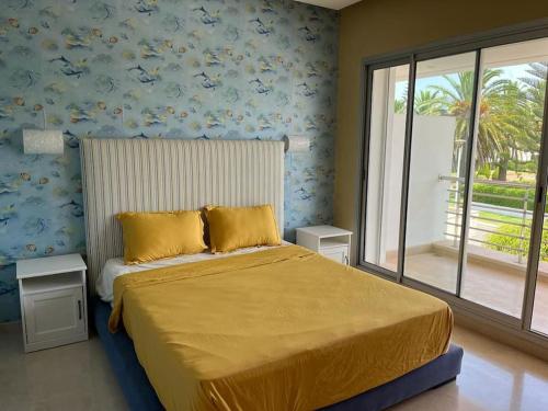 布兹尼盖Belle Villa à Bouznika plage - Golf Bouzbay的一间卧室配有一张带黄色床单的床和一扇窗户。