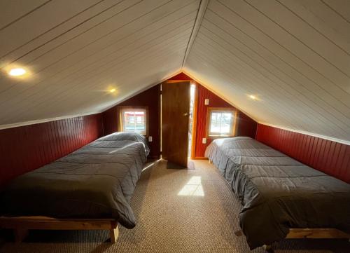 纳塔列斯港Corner Hostel Puerto Natales的红色墙壁客房的两张床