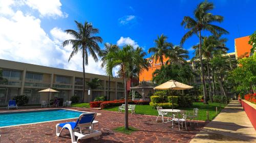 坦皮科波萨达德坦皮科酒店的一个带游泳池、椅子和棕榈树的度假村