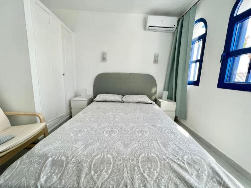 马斯帕洛马斯Bungalow playmar 24的卧室配有带灰色棉被的床