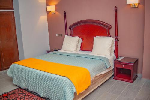 黑角Mayombe Arena Hotel的一间卧室配有一张大床和红色床头板