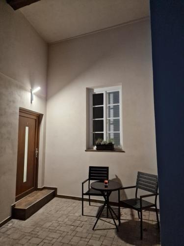 伊钦Apartmán Anežka 3 s vířivou vanou的一间设有两把椅子、一张桌子和一个窗户的房间
