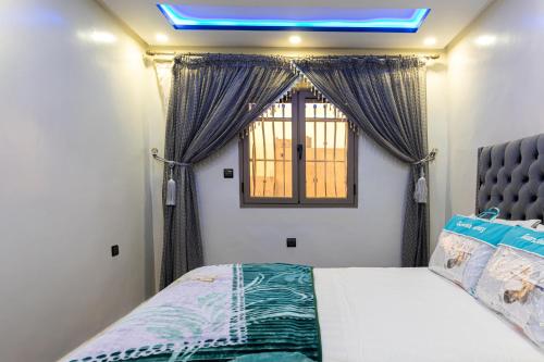 达赫拉ADAM APPARTEMENTS的一间卧室配有床和带窗帘的窗户