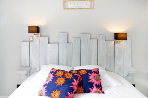 乌瑞基尼Appartement, 2 à 4 pers的一张白色的床,上面有两个色彩缤纷的枕头