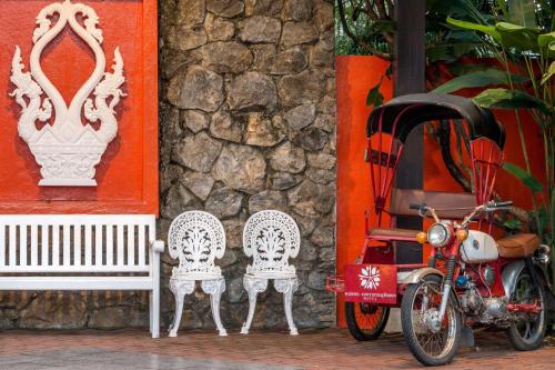 琅勃拉邦Angsana Maison Souvannaphoum Hotel的一辆摩托车停在两把椅子和一座建筑旁边