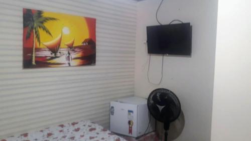 巴拉那瓜Pousada Tia Tina的一间设有床铺和墙上电视的房间