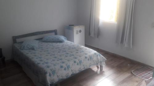 巴拉那瓜Pousada Tia Tina的一间卧室设有一张床、一个窗口和一台冰箱