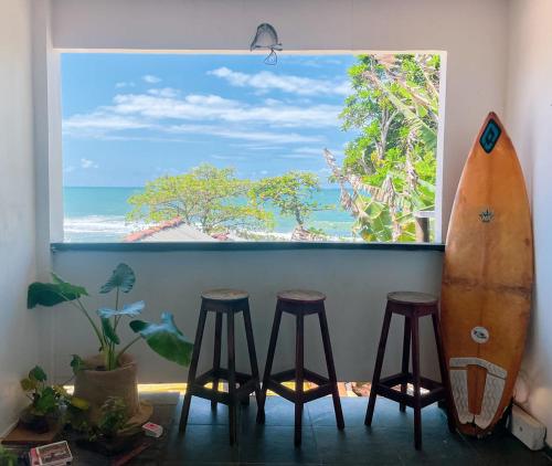 伊塔卡雷LahSelva Pousada Hostel的窗户,有冲浪板和凳子在房间里