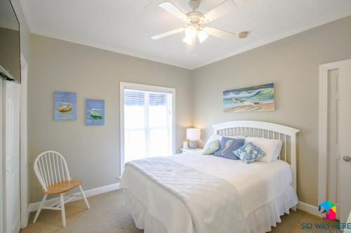 泰比岛Beachfront Oasis At Tybee Island的一间卧室配有一张带吊扇和窗户的床。