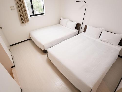 石垣岛KARCHIBE ISHIGAKI的小房间设有两张床和窗户