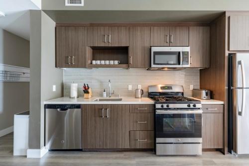 洛杉矶New Construction Modern Luxury Views Pool & Patio的厨房配有木制橱柜、炉灶和微波炉。