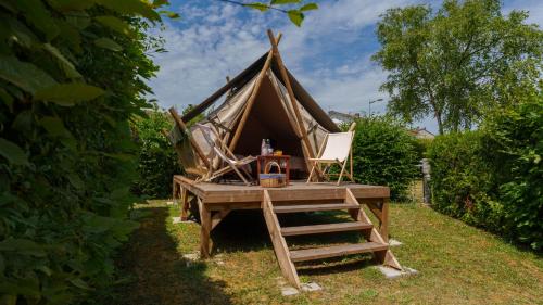 维泰勒Camping Vittel的草上带椅子和桌子的圆锥形帐篷