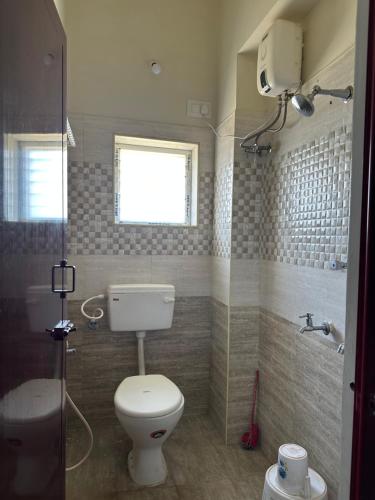 马杜赖Jothi Residency的一间带卫生间和淋浴的浴室以及窗户。