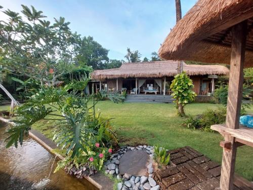 塞莱马德加Bali Beach Eco Villas Pondok Matekap的前面有池塘的房子