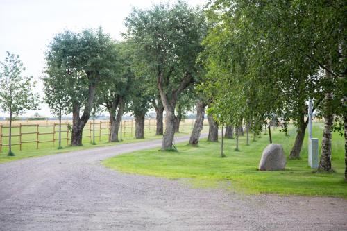 VåxtorpÄngagården - Gårdshuset的一条有树木和栅栏的草地上的碎石路