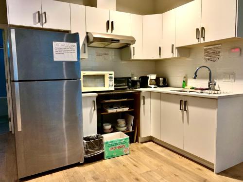 萨里Deluxe House的厨房配有白色橱柜和不锈钢冰箱