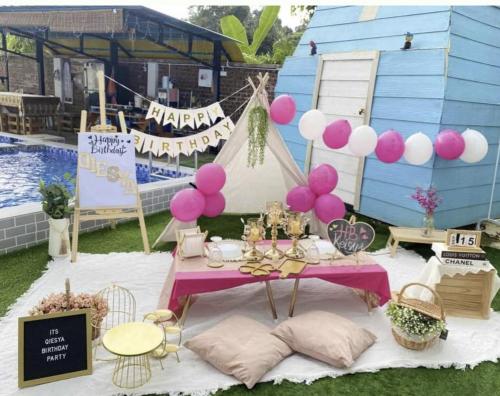 Casa LiLa Tiny Stay & Pool Kota Bharu,free wifi,free parking的一张桌子,旁边是粉红色和白色的气球