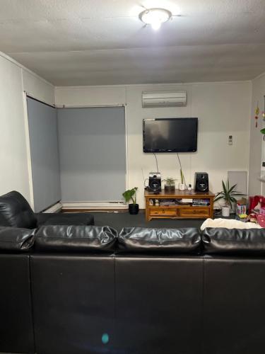 WarraneRosy的客厅配有黑色真皮沙发和平面电视。