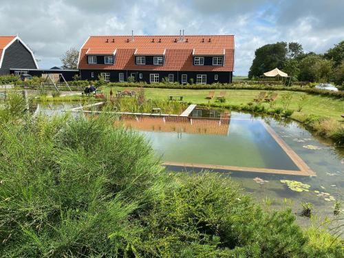 登堡Nieuw Leven Texel的楼前有池塘的房子