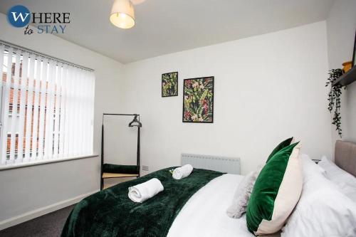 KentonStylish 3 bedroom property Newcastle的一间卧室配有一张带绿床单和枕头的床。