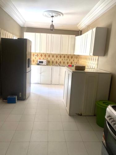 姆布尔Hôtel Ami Bamba的厨房配有白色橱柜和黑色冰箱。